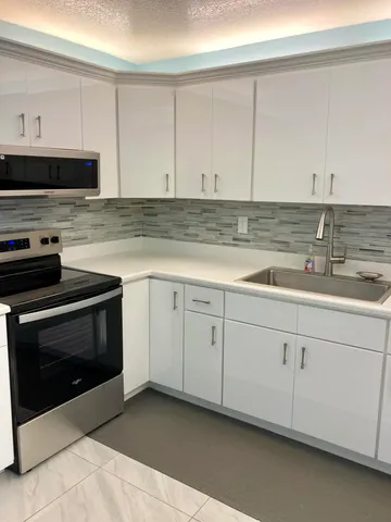 a kitchen with granite countertop white cabinets and white appliances