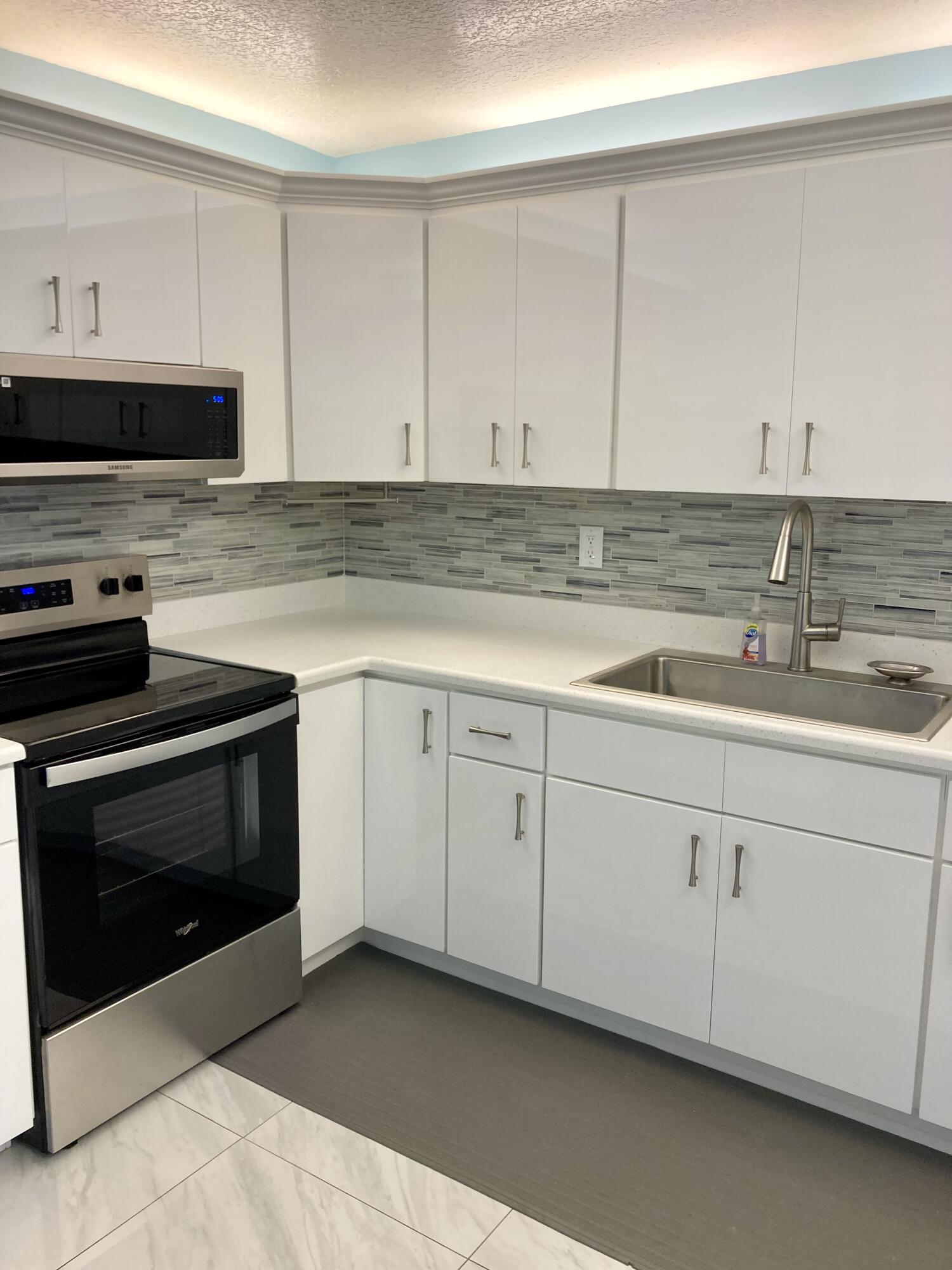 950 South Kanner Highway, Unit E23 Stuart, FL 34994 - Photo 6 of 15 a kitchen with granite countertop white cabinets and white appliances