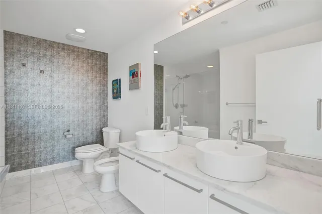 a bathroom with a double vanity sink toilet and shower