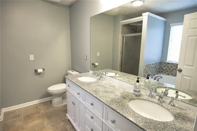 a bathroom with a granite countertop sink toilet and mirror
