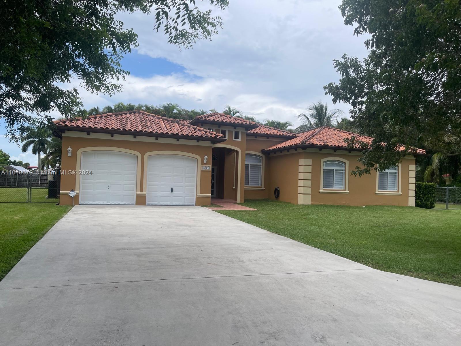 32050 Southwest 204th Avenue Homestead, FL 33030 - Photo 2 of 36 a front view of a house with a garden and yard