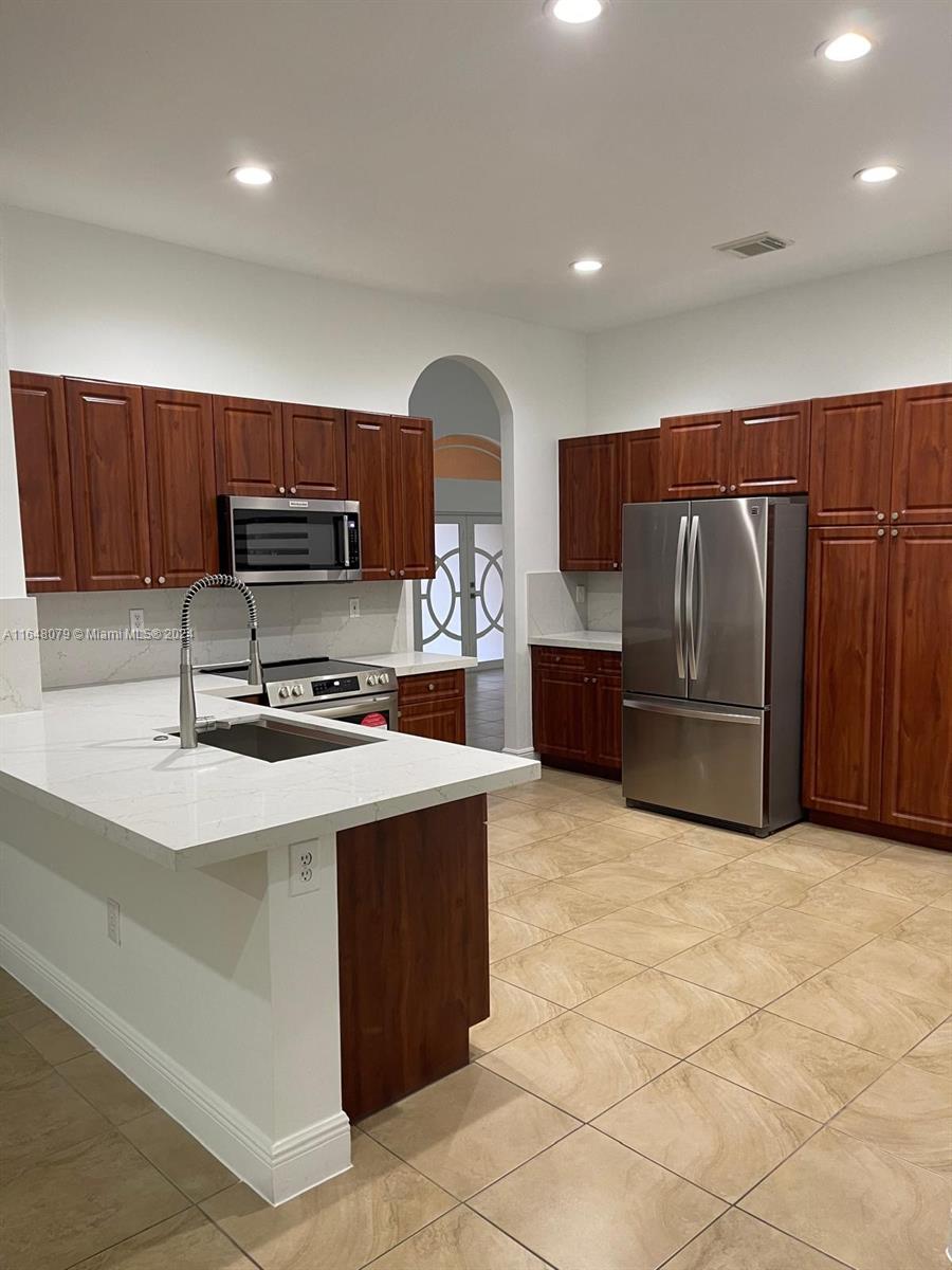 32050 Southwest 204th Avenue Homestead, FL 33030 - Photo 23 of 36 a kitchen with stainless steel appliances a stove a sink a refrigerator and a cabinets