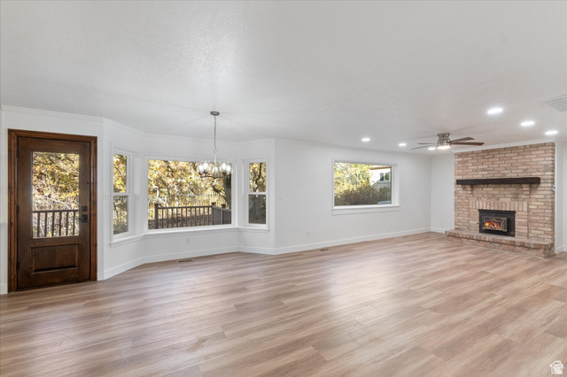2078 Spring Oaks Drive Springville, UT 84663 - Photo 15 of 40 Unfurnished dining/family room featuring light wood-style floors, hanging lights, ceiling fan, and a brick fireplace
