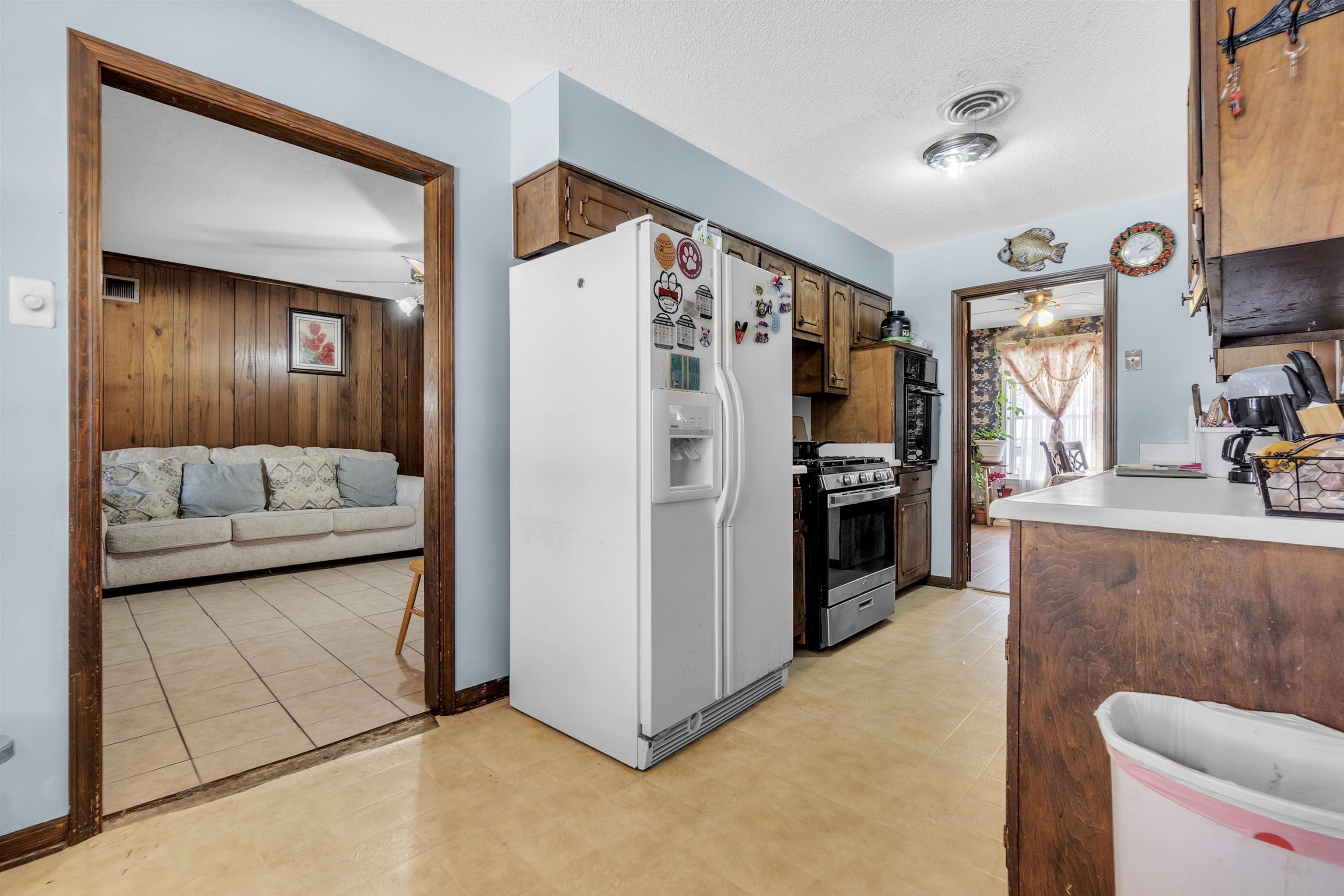 3463 Dupre Street Memphis, TN 38115 - Photo 12 of 25 Kitchen featuring white fridge with ice dispenser, light countertops, stainless steel gas stove, wood walls, and a textured ceiling