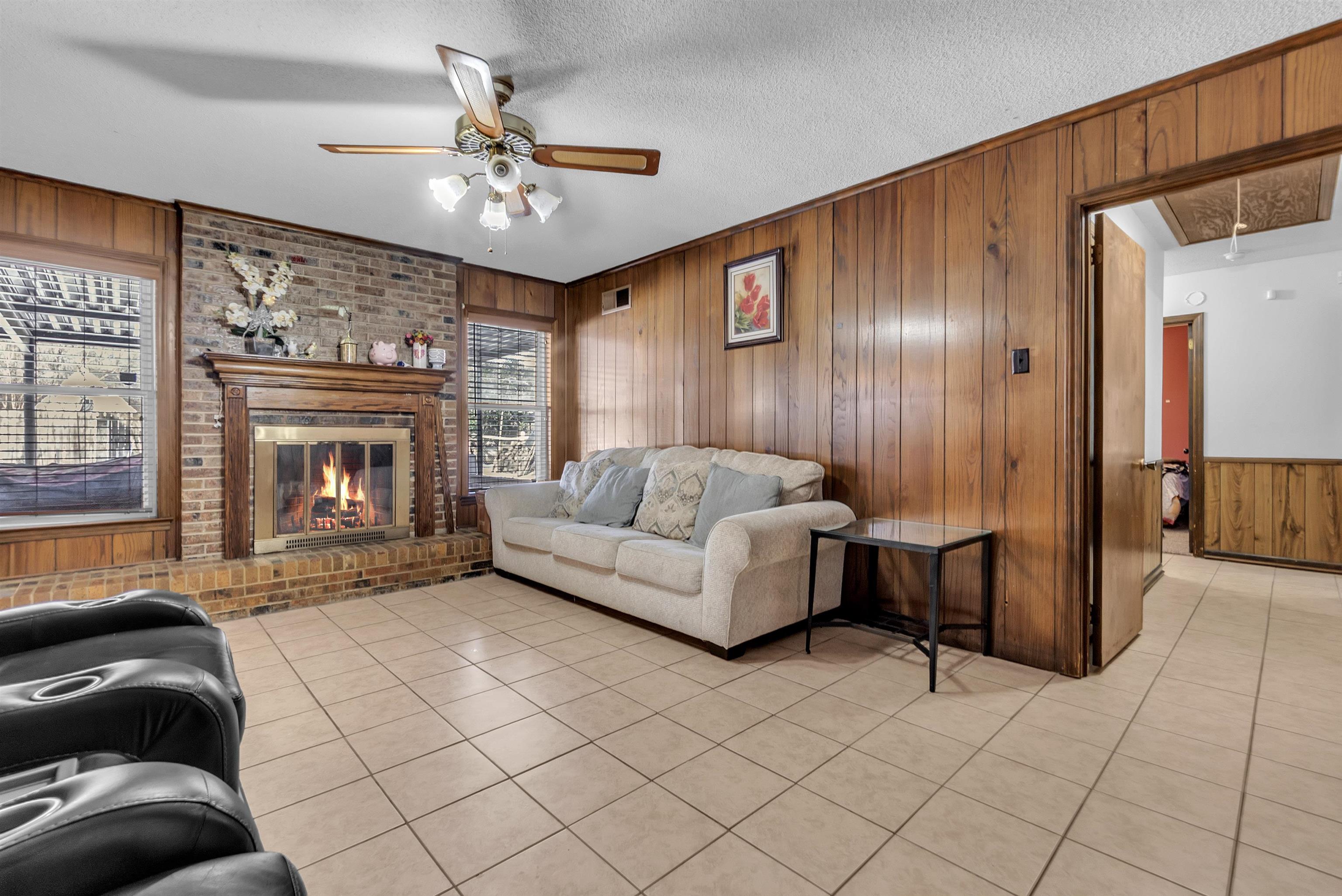 3463 Dupre Street Memphis, TN 38115 - Photo 14 of 25 Living area featuring wooden walls, attic access, a textured ceiling, light tile patterned floors, and a fireplace