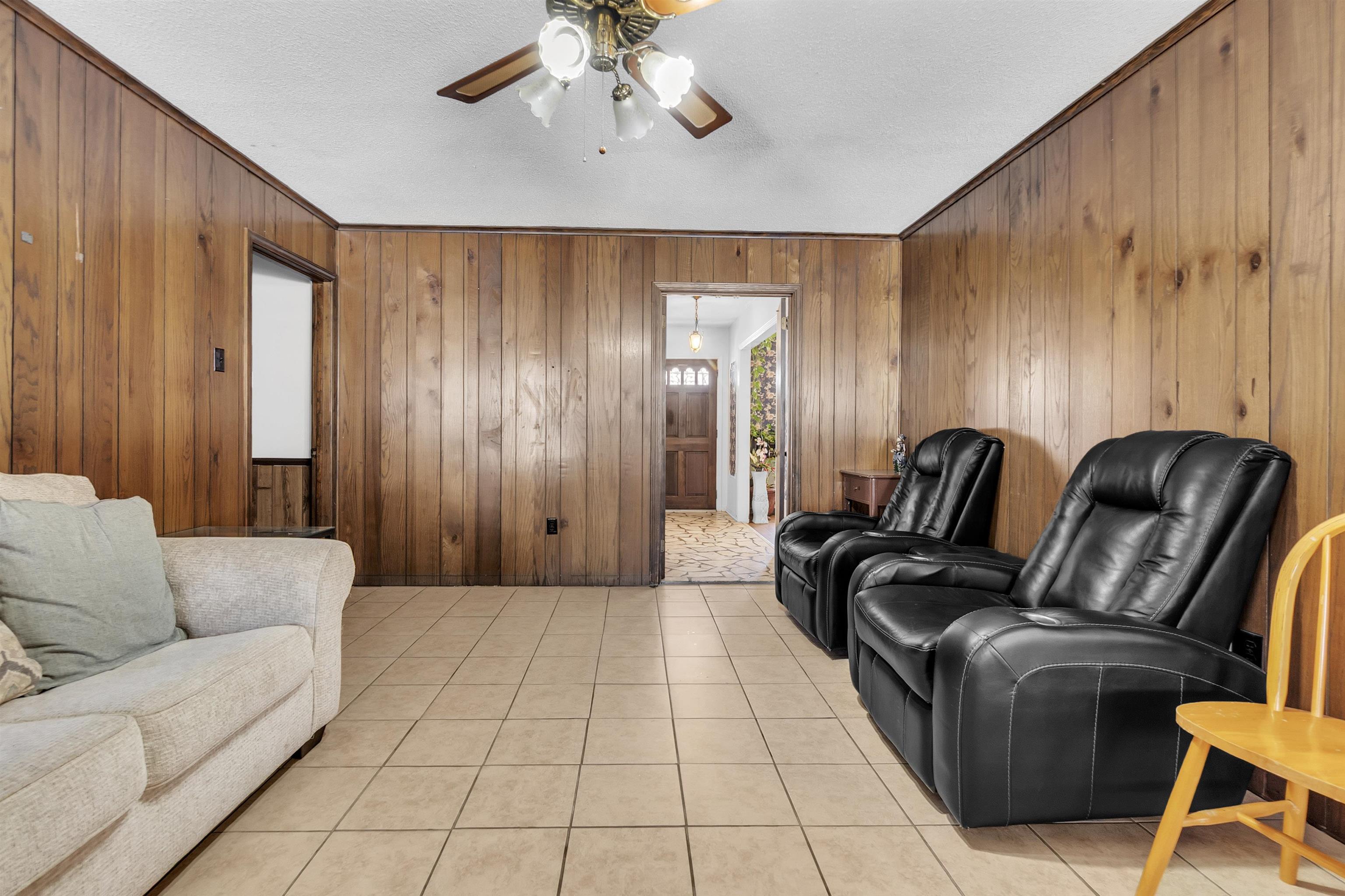3463 Dupre Street Memphis, TN 38115 - Photo 9 of 25 Living room with ceiling fan, a textured ceiling, light tile patterned flooring, wooden walls, and ornamental molding