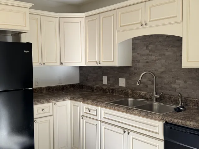 a kitchen with granite countertop white cabinets and refrigerator