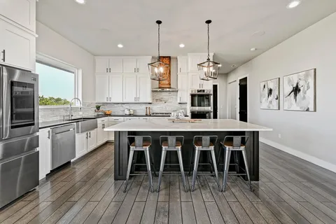 a kitchen with stainless steel appliances granite countertop a kitchen island hardwood floor sink stove dining table and chairs