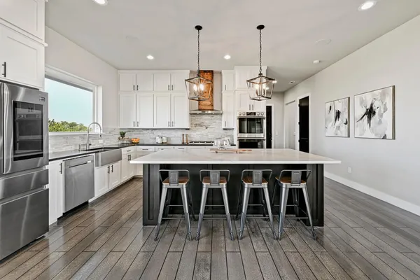 a kitchen with stainless steel appliances granite countertop a kitchen island hardwood floor sink stove dining table and chairs