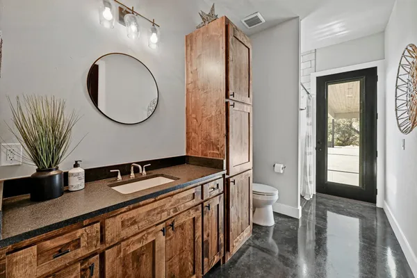 a bathroom with a granite countertop sink a toilet a mirror and shower