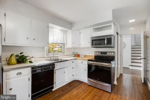 a kitchen with granite countertop a stove a sink and dishwasher with wooden floor