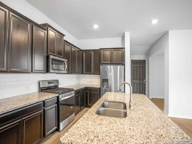 a kitchen with stainless steel appliances granite countertop a sink stove microwave and refrigerator