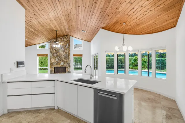 a kitchen with granite countertop a sink and white cabinets next to a window