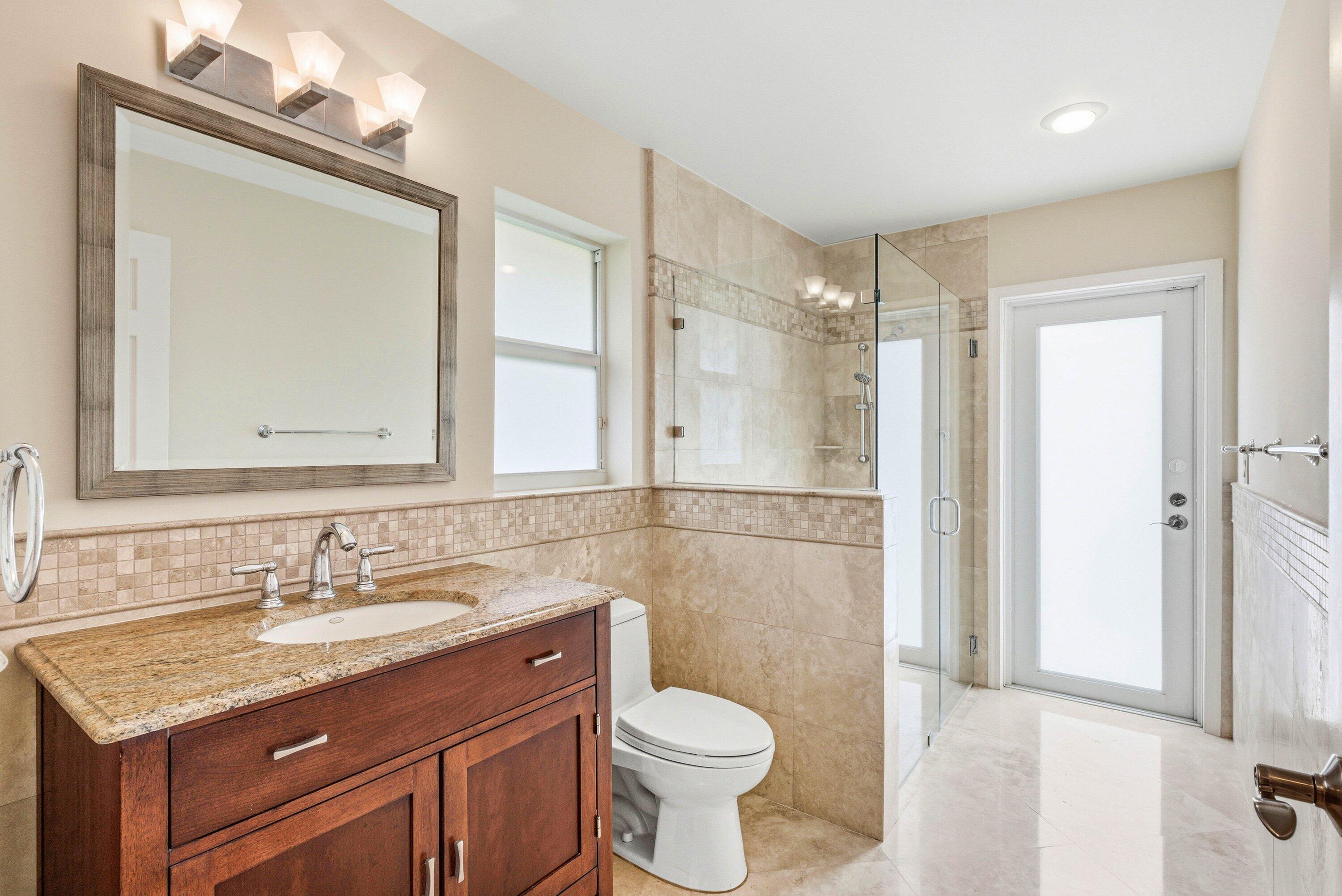 4720 Northwest 28th Avenue Boca Raton, FL 33434 - Photo 40 of 47 a bathroom with a granite countertop sink toilet and shower