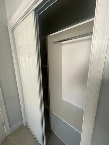 an empty room with a fan & a window