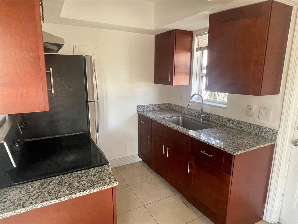 363 Southwest 15th Street, Unit 4 Pompano Beach, FL 33060 - Photo 7 of 16 a kitchen with stainless steel appliances granite countertop a sink stove and refrigerator