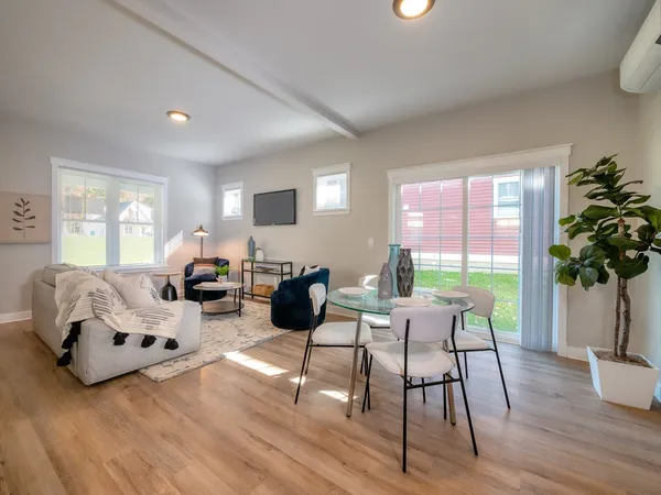 a living room with furniture hard wood floor and a floor to ceiling window