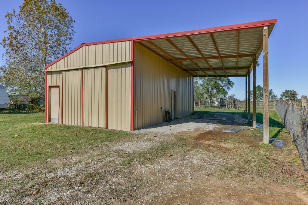 34366 Owens Road Hempstead, TX 77445 - Photo 34 of 46 Metal equipment barn with an enclosed storage area and a large covered lean-to, providing versatile space for tractors, trailers, hay, ranch equipment, or workshop use.