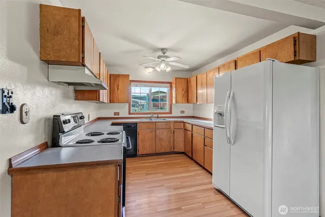 a kitchen with stainless steel appliances a stove a sink dishwasher a refrigerator and cabinets with wooden floor