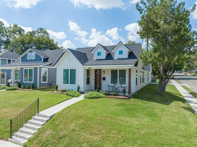 a view of a white house with a big yard and large trees