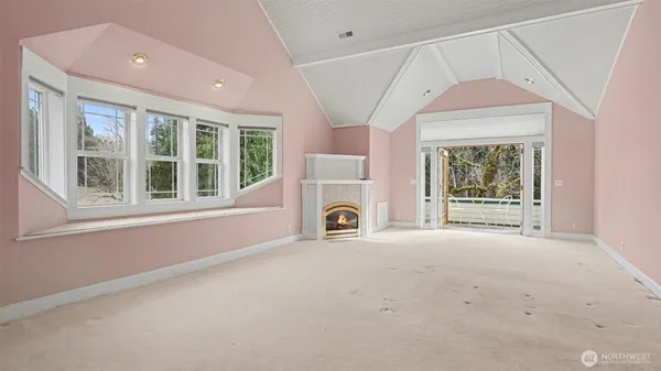 an empty room with windows and fireplace