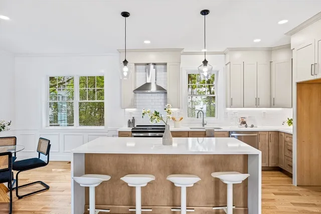 a kitchen with kitchen island granite countertop a table chairs a sink and a window