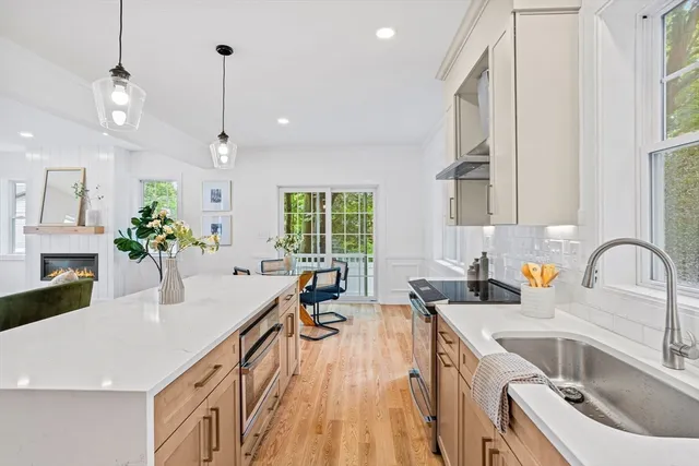 a kitchen with stainless steel appliances a sink dishwasher a stove a kitchen island with wooden cabinets and floor