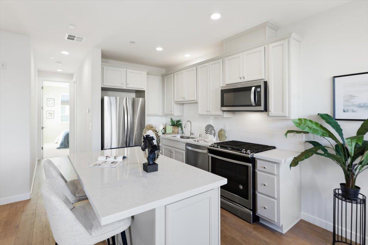 1910 Joshua Tree Circle Milpitas, CA 95035 - Photo 7 of 43 a kitchen with a stove a sink a microwave a dining table and chairs