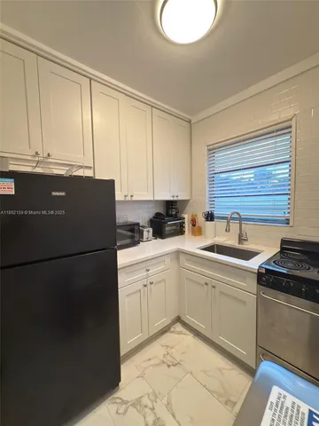 a kitchen with a refrigerator sink and cabinets