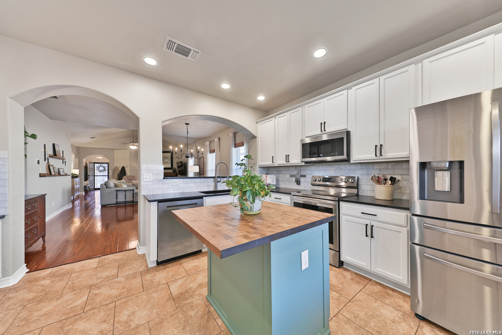 10414 Pecne Path Helotes, TX 78023 - Photo 18 of 42 a kitchen with stainless steel appliances granite countertop a refrigerator a stove top oven a sink dishwasher and white cabinets with wooden floor