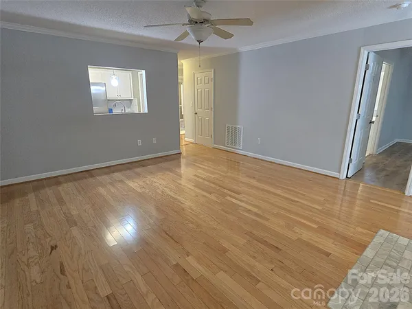 a view of an empty room with wooden floor and windows