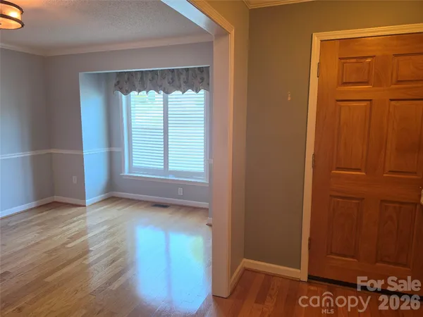 an empty room with wooden floor closet and windows