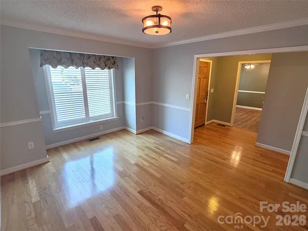an empty room with wooden floor cabinet and windows