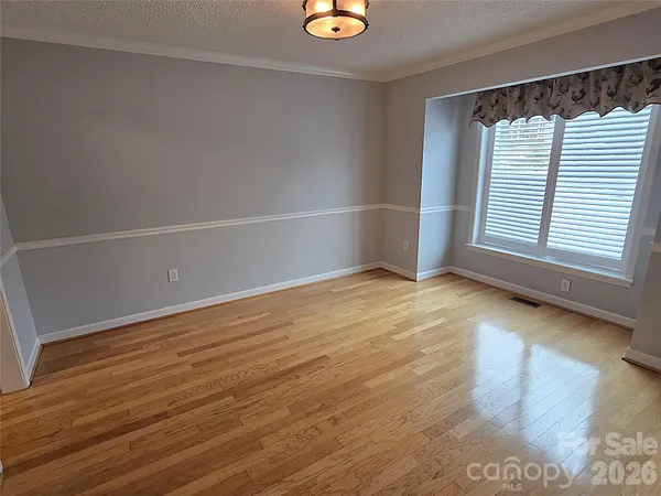 an empty room with wooden floor & cabinet and a kitchen