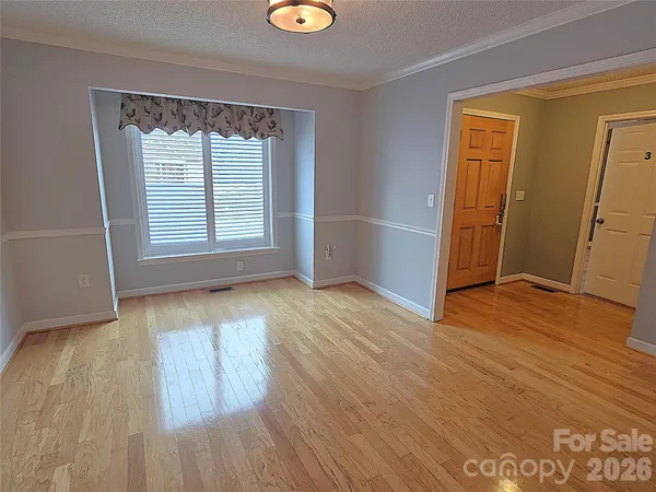an empty room with wooden floor a fireplace and windows