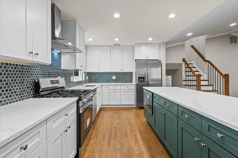 a kitchen with kitchen island granite countertop wooden floors and white cabinets