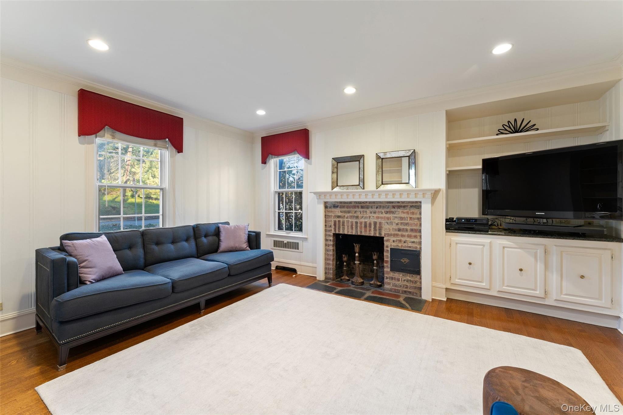 24 Olmsted Road Scarsdale, NY 10583 - Photo 13 of 39 a living room with furniture flat screen tv and a fireplace