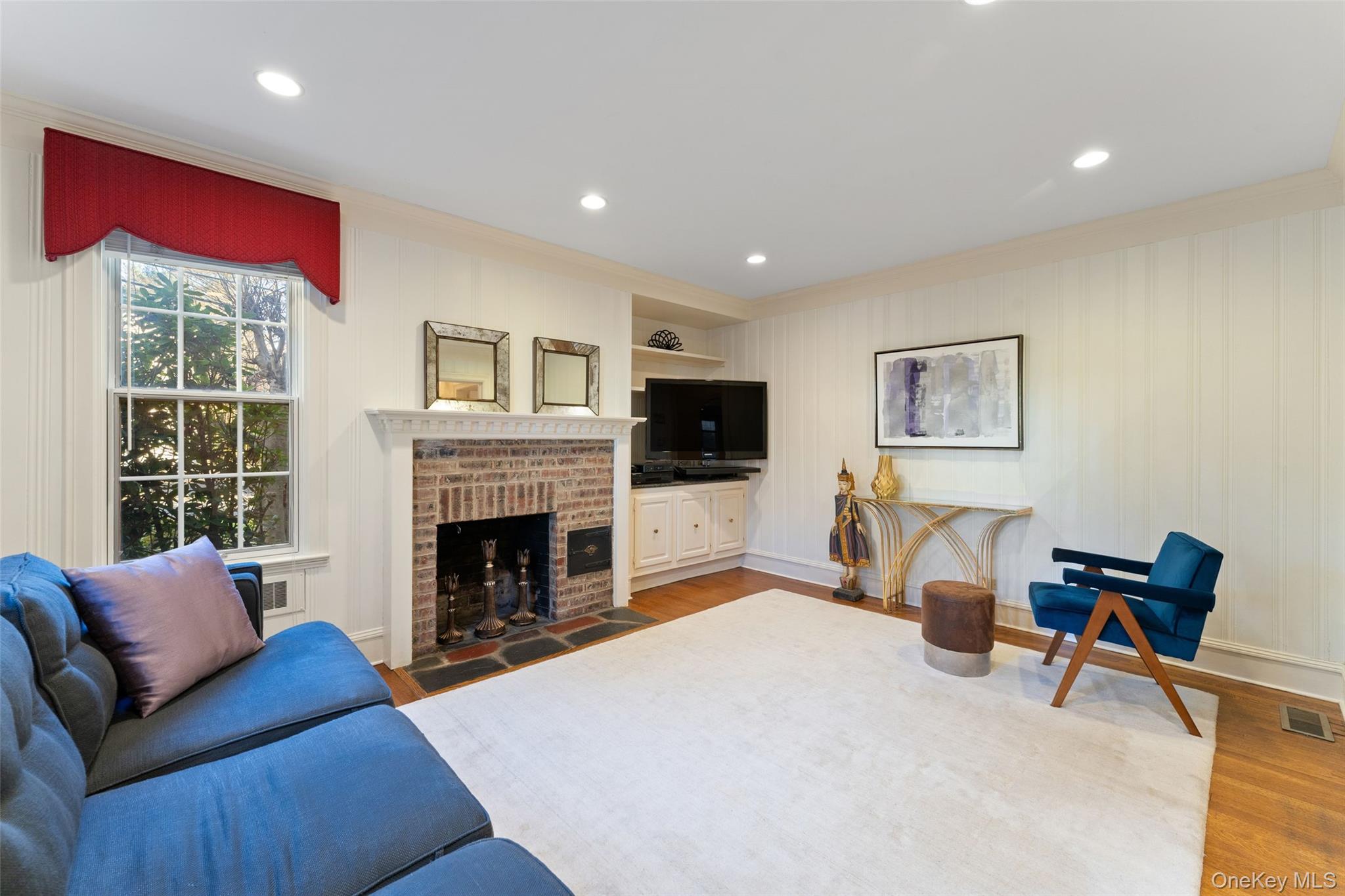 24 Olmsted Road Scarsdale, NY 10583 - Photo 14 of 39 a living room with furniture flat screen tv and a fireplace
