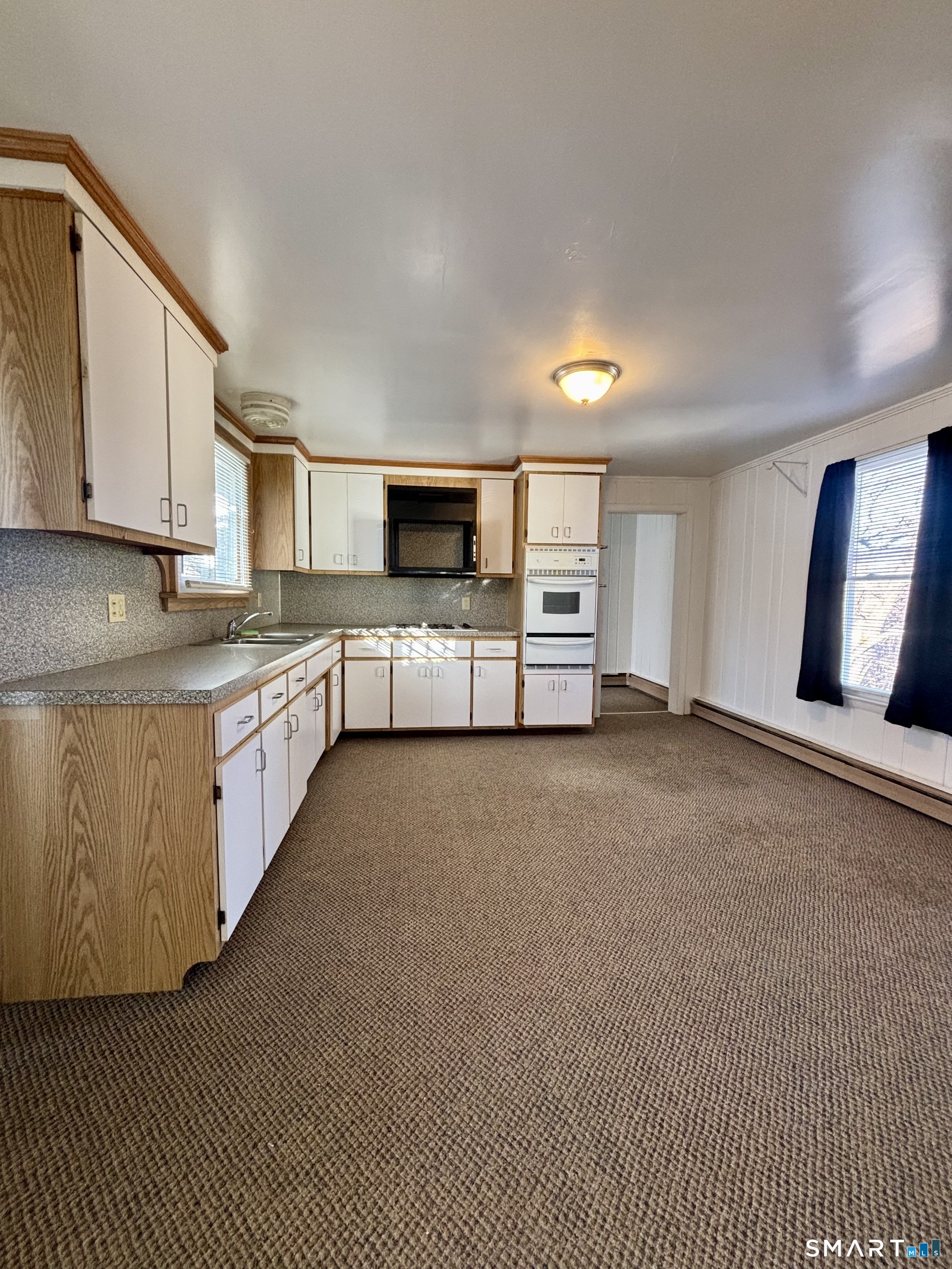 73 Peck Street, Unit 2 Norwich, CT 06360 - Photo 2 of 10 a large white kitchen with stainless steel appliances granite countertop a lot of cabinets and wooden floor