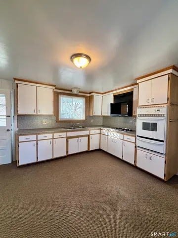 a kitchen with stainless steel appliances a stove and white cabinets