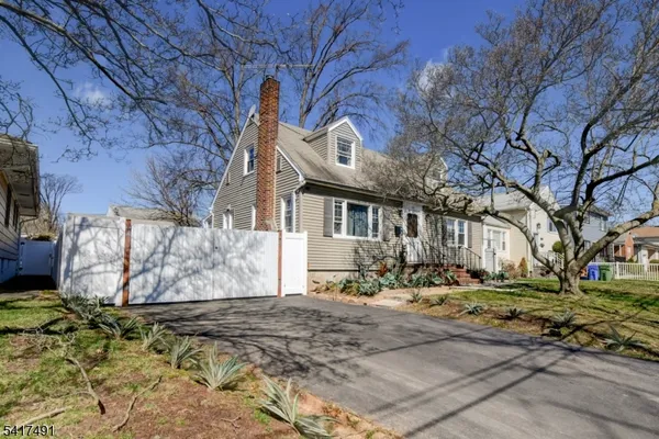 a kitchen with stainless steel appliances kitchen island granite countertop a refrigerator a sink dishwasher and white cabinets with wooden floor
