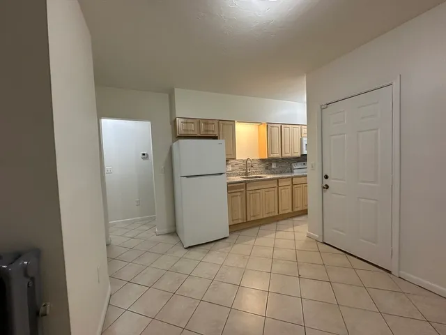 a kitchen with a refrigerator a stove top oven and white cabinets