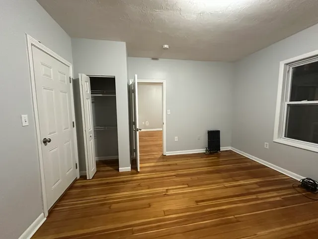 a view of an empty room with window and wooden floor