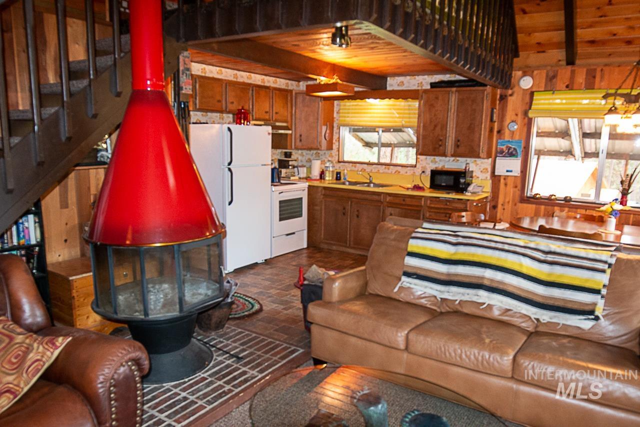 225 Mesplie Road Placerville, ID 83666 - Photo 16 of 39 Living room featuring stairway, a wooden ceiling with exposed beams, and a wood stove