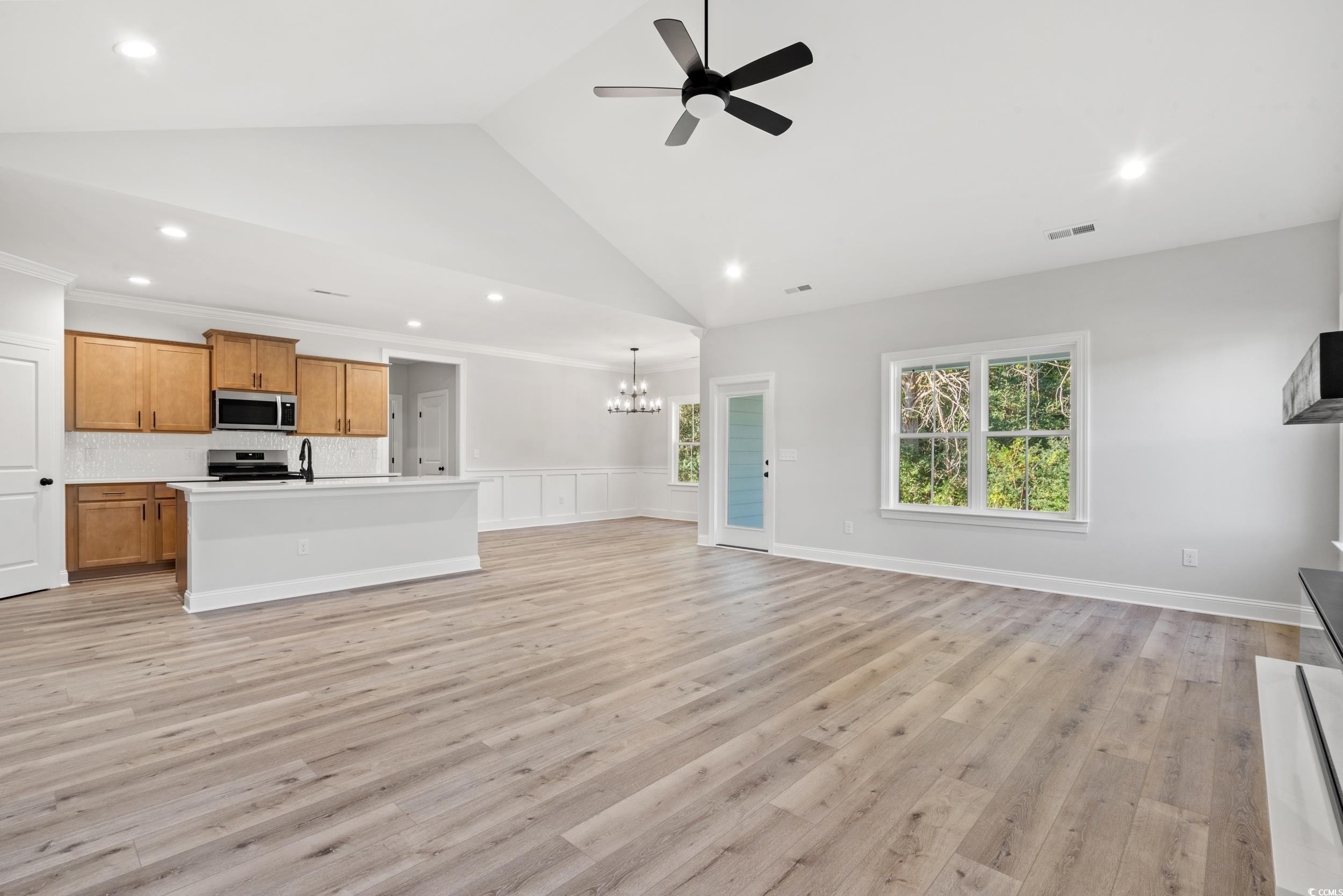 1201 Crooked Hook Road North Myrtle Beach, SC 29582 - Photo 8 of 23 Unfurnished living room featuring light wood-style flooring, high vaulted ceiling, plenty of natural light, a large fireplace, and a ceiling fan