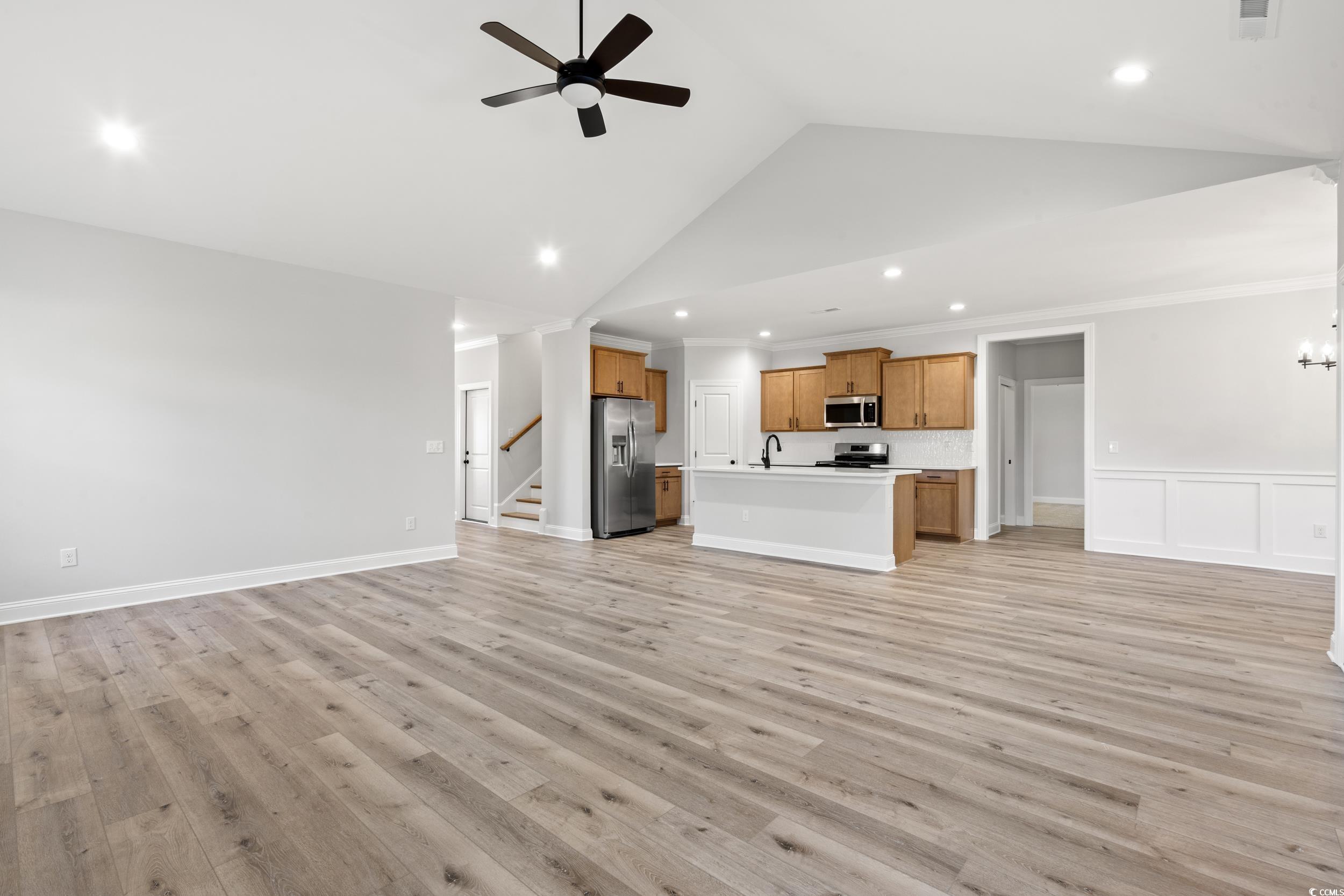 1201 Crooked Hook Road North Myrtle Beach, SC 29582 - Photo 9 of 23 Unfurnished living room featuring a wainscoted wall, light wood-style floors, a decorative wall, ceiling fan, and a chandelier