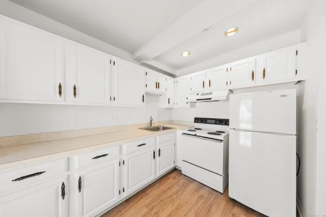 a kitchen with cabinets stainless steel appliances and wooden floor