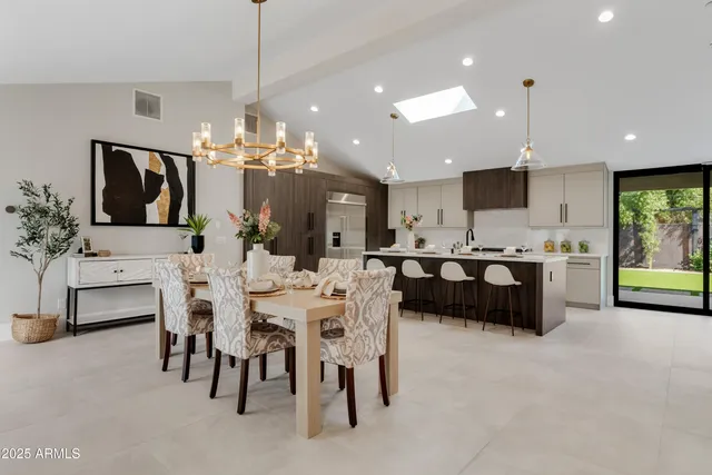 a kitchen island with stainless steel appliances lots of white furniture a chandelier a sink and a refrigerator
