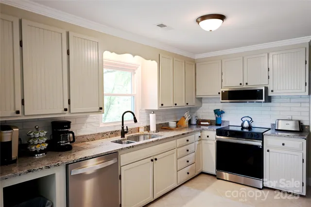 a kitchen with stainless steel appliances granite countertop a sink dishwasher a stove and cabinets