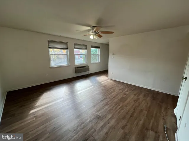 an empty room with wooden floor chandelier fan and windows